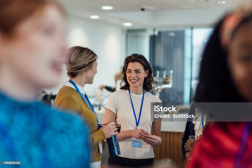 Group of adults wearing conference badges engaged in conversation in a modern indoor space.